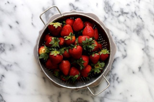 a colander filled with fresh strawberries 