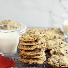 Stack of the best chocolate chip cookies on a cooking rack with glass of milk