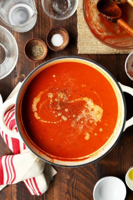 Adding a splash of cream to pot of tomato soup.