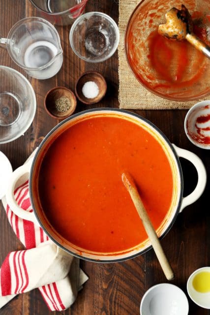 Creamy tomato soup recipe in a pot with wooden spoon.