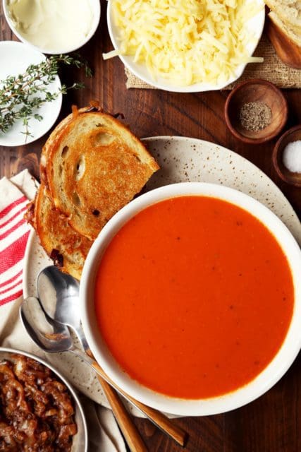 Creamy tomato soup recipe with a grilled cheese sandwich on the side.