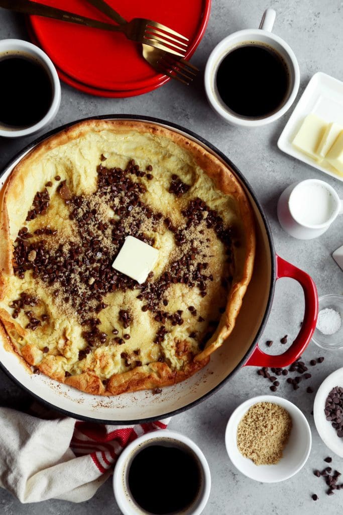 Freshly cooked Dutch baby sprinkled with chocolate chips and brown sugar