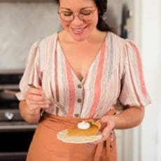 Joy the Baker holds a slice of sweet potato pie on a small plate.