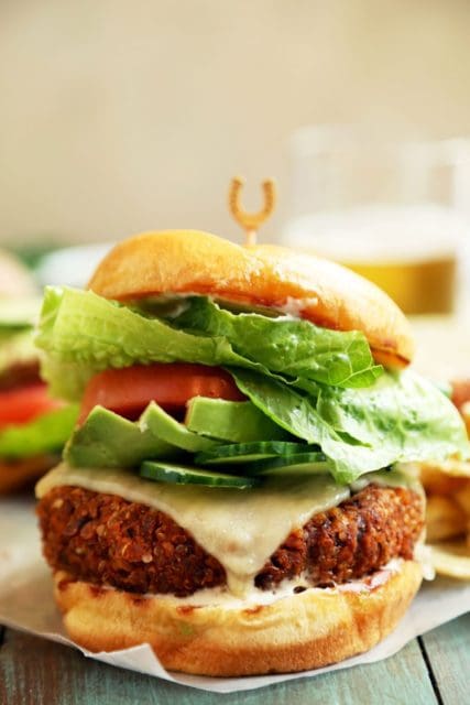 Veggie burger on a bun stacked with avocado lettuce and tomato