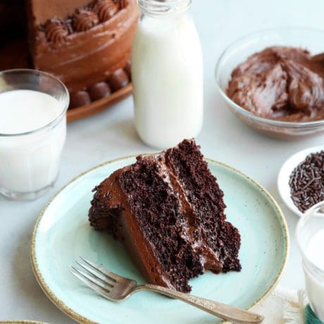 Slice of chocolate cake with chocolate frosting on a plate with a fork.