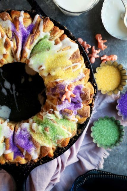 A New Orleans King Cake baked in a cast iron skillet with green, gold, and purple sprinkles