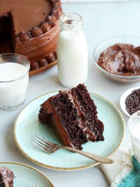 Slice of chocolate cake with chocolate frosting on a plate with a fork.