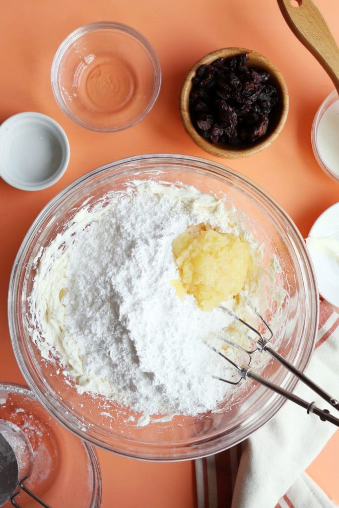 Powdered sugar and crushed pineapple in a bowl with cream cheese for frosting.