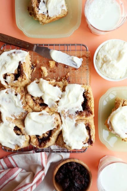 Cream cheese frosting on a small knife with cinnamon rolls.