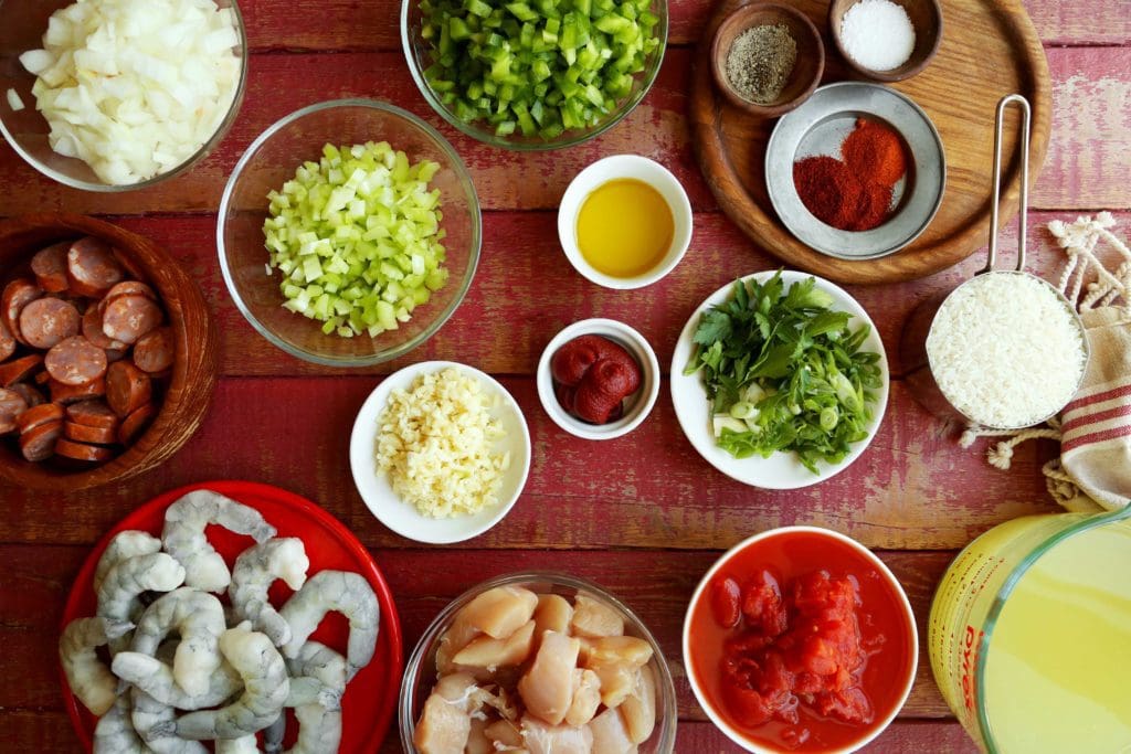 Food photography: ingredients for jambalaya in small bowls, chicken, shrimp, shopped celery, green peppers, and onions.