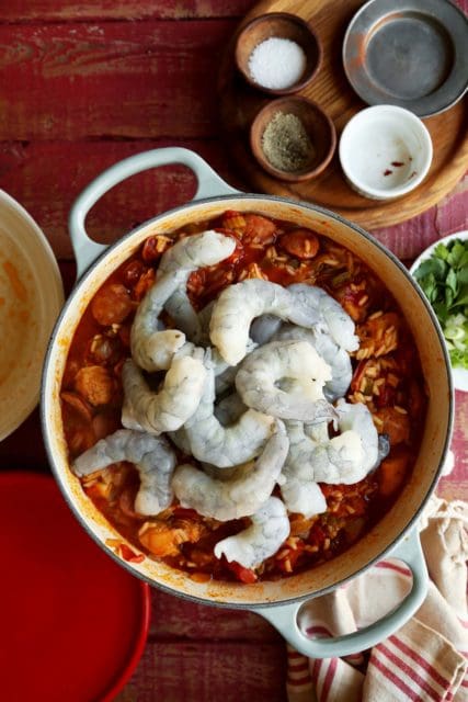 A cooking pot of jambalaya, raw shrimp added.