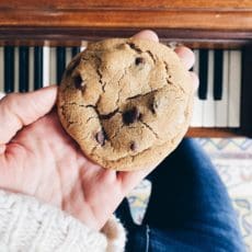 One chocolate chip cookie being held in a hand.