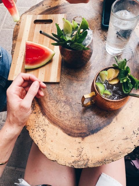 Round table with two cocktails in copper cups and a wedge of watermelon