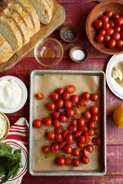 Cherry tomatoes on a parchment lined baking sheet for roasting.