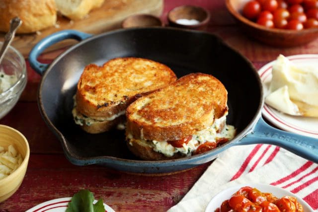 Two lasagna grilled cheese sandwiches grilling in a skillet.
