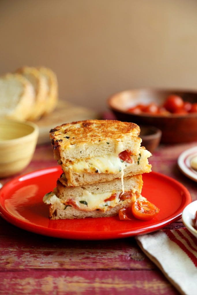 Lasagna Grilled Cheese Sandwiches sliced in half and oozing melted cheese.