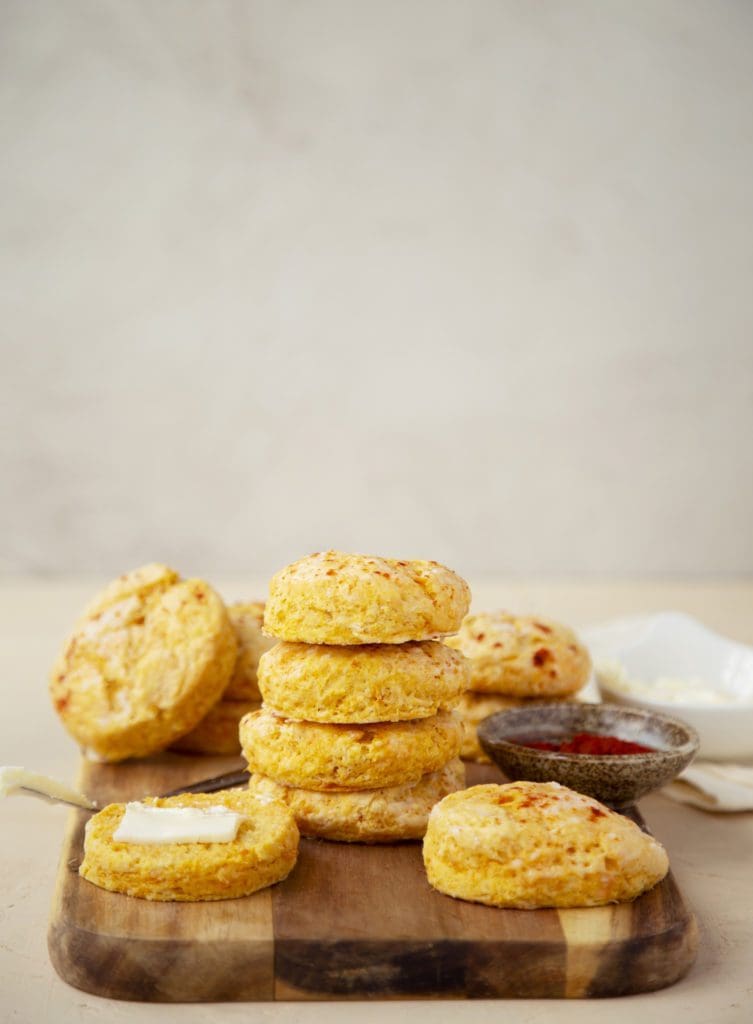 Sweet potato biscuits stacked on a cutting board with butter.