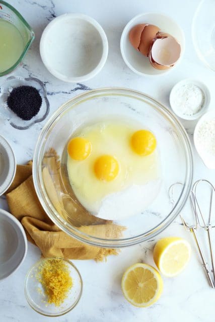 Eggs and sugar in a clear bowl for whisking a lemon bars recipe.