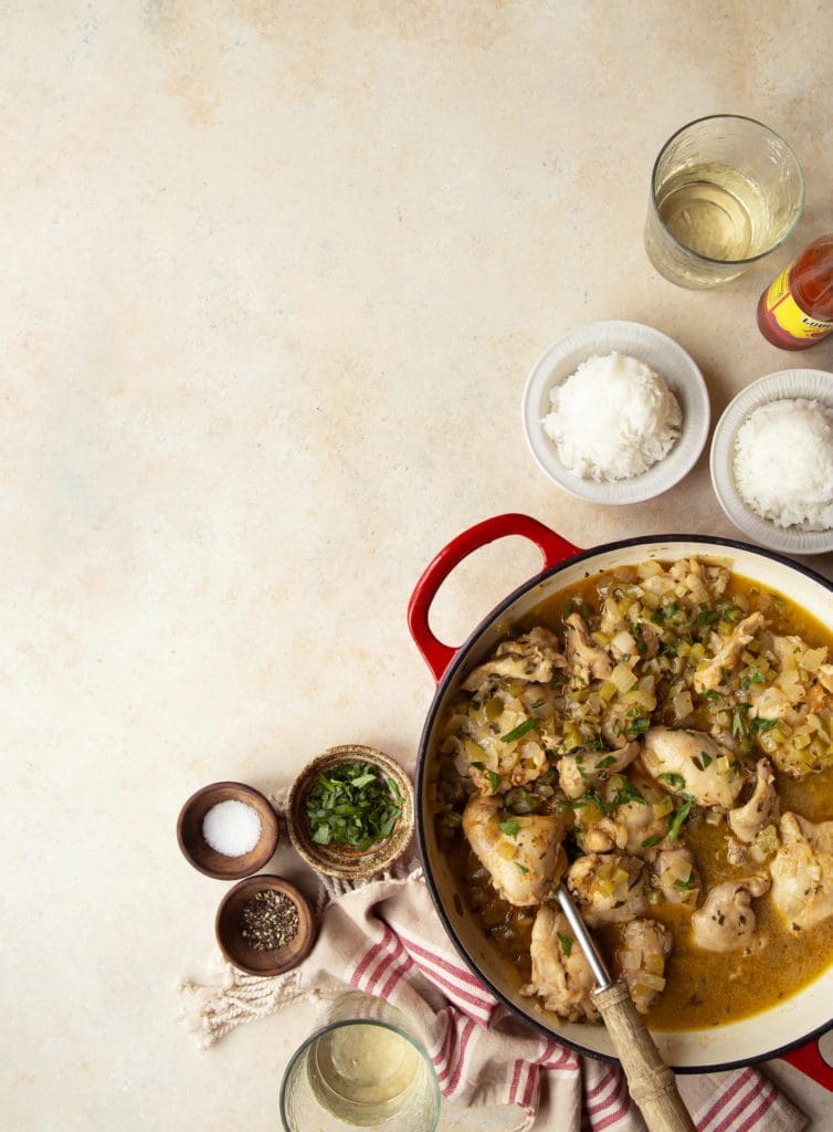 Cooked smothered chicken recipe in a pan with herbs and rice.