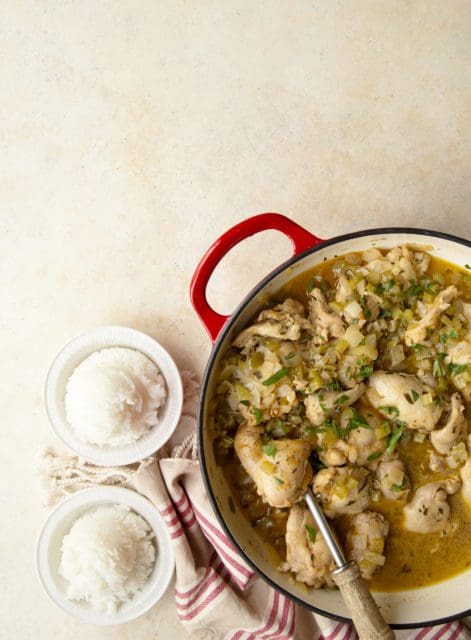 Smothered chicken recipe in a red pan with rice.