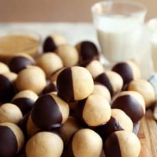 Peanut butter balls dipped in chocolate and piled on a board.