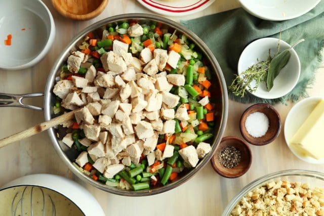 Adding cubed turkey to vegetables for pot pie.