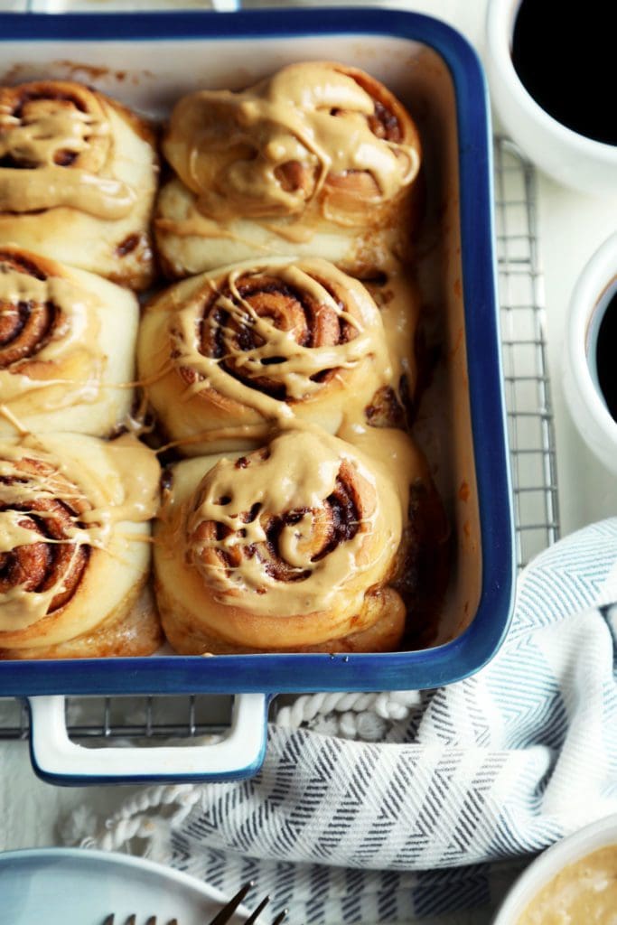 glazed tray of small batch overnight cinnamon rolls in a pan on rack.