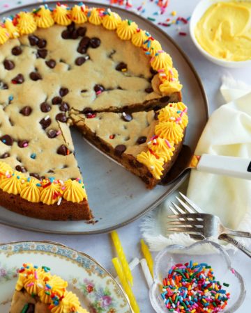 Sliced cookie cake with forks, candles, and sprinkles.