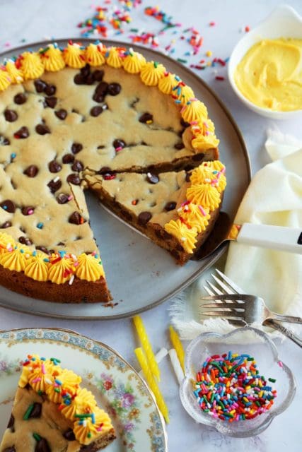 Sliced cookie cake with forks, candles, and sprinkles.