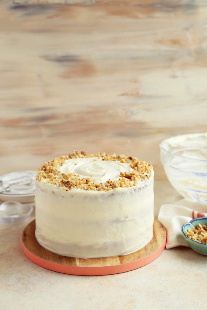 Whole frosted carrot cake topped with walnuts/