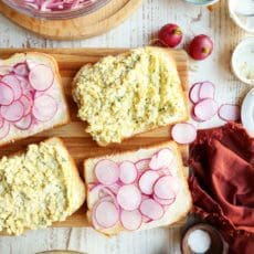 Making egg salad sandwiches.s Two pieces of bread with radishes and onions.