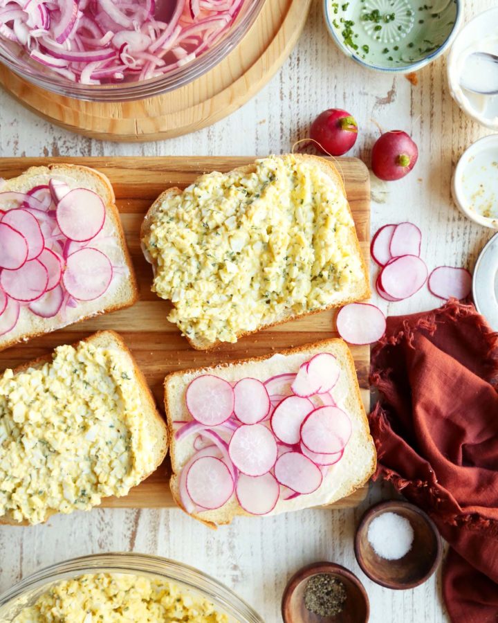 Making egg salad sandwiches.s Two pieces of bread with radishes and onions.