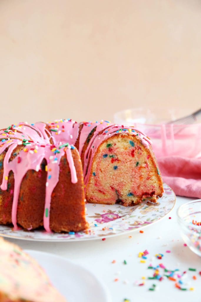 Funfetti cake sliced with pink swirl and pink glaze.
