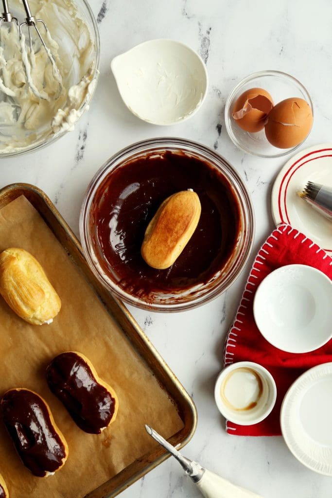 dipping chocolate eclairs in melted chocolate.