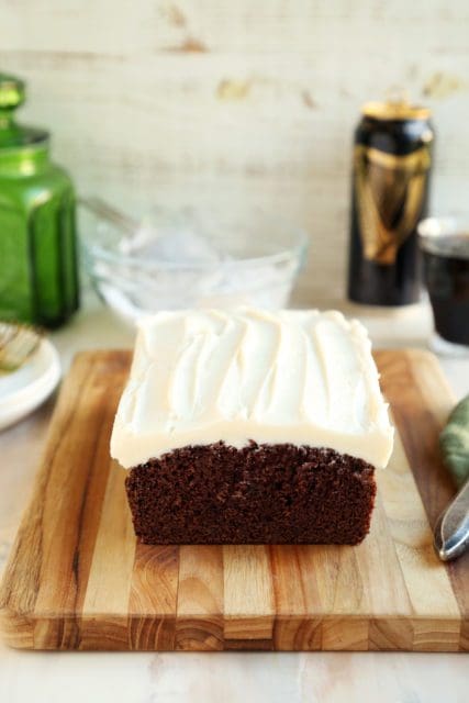 Loaf of chocolate stout cake topped with cream cheese frosting.