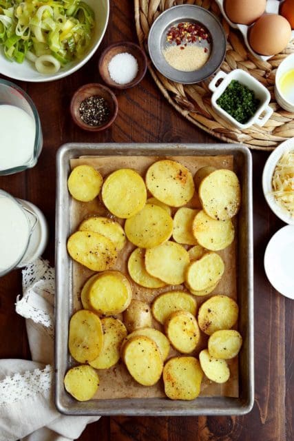 Roasted potato rounds on a baking sheet for quiche recipe.