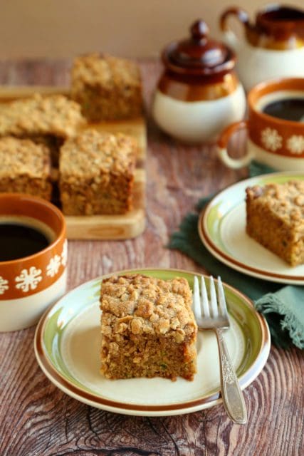 Slices of coffee cake on small plates and a cutting board with coffee.