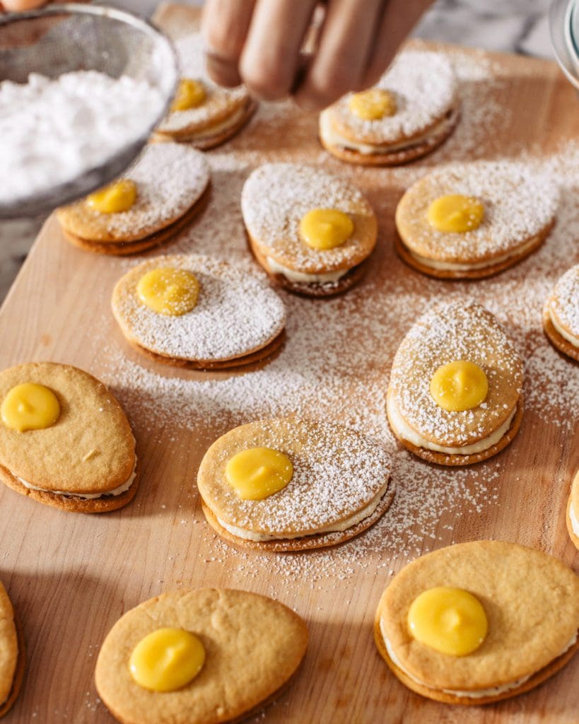 Dusting powdered sugar over lemon cookies.