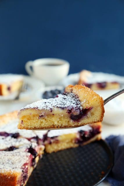 A slice of lemon blueberry gooey butter cake held on a cake slicer.