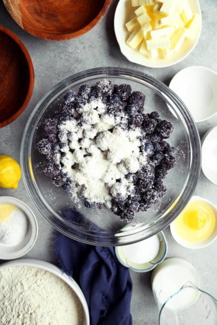adding dry ingredients to blueberry cobbler recipe.