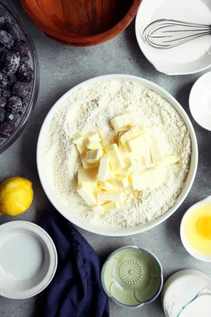 adding butter to blueberry cobbler topping