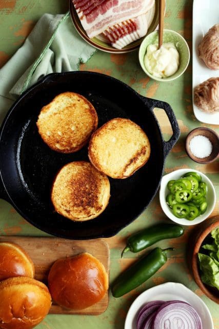 brioche buns toasting in cast iron skillet for smash burgers.