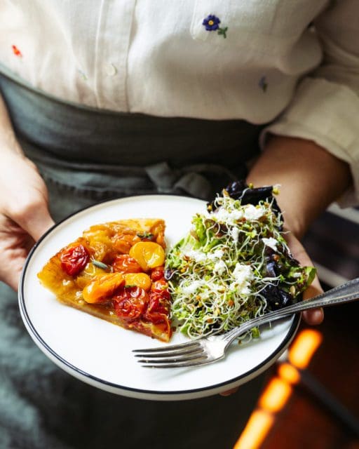 Sliced tomato pie recipe on plate with salad 