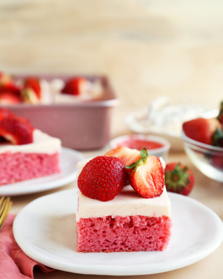 strawberry sheet cake on a plate with strawberries on top.