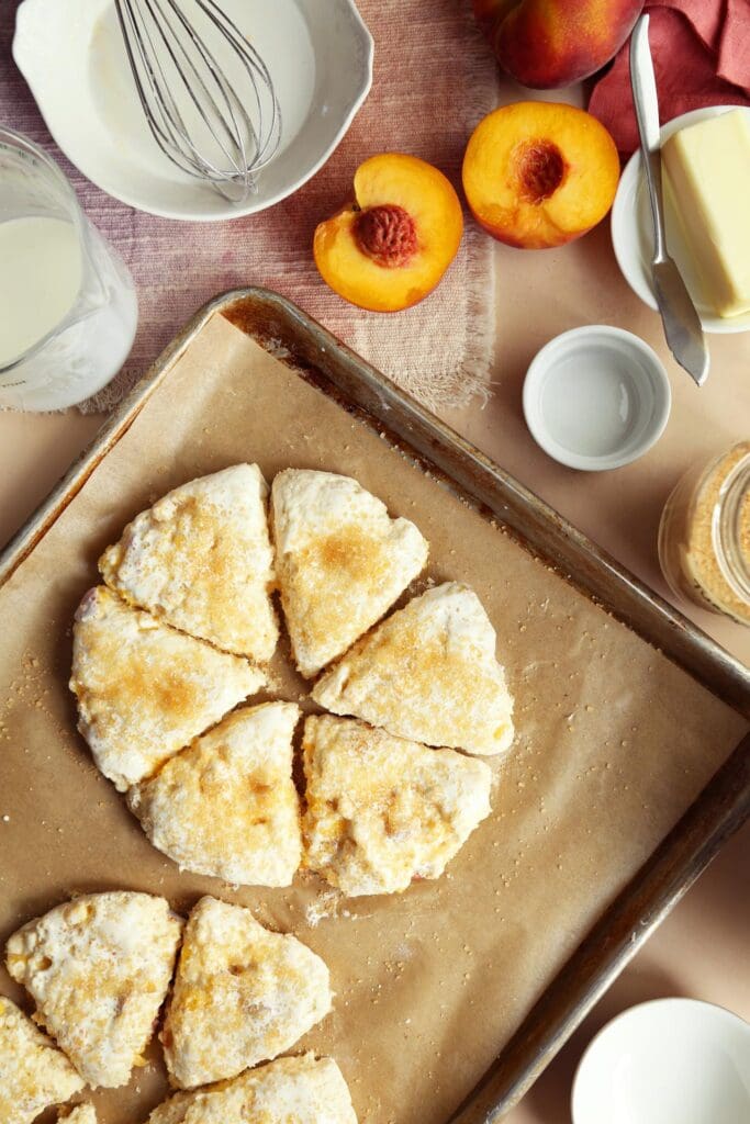 Peach scone dough cut in wedges on a baking sheet