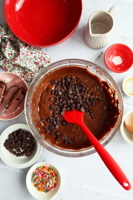 Adding chocolate chips to brownie cookie batter.