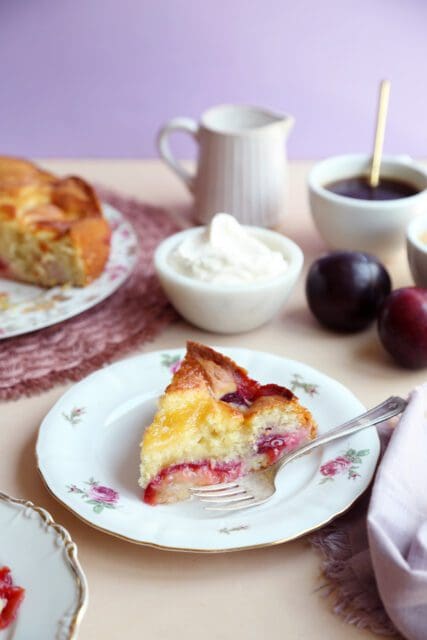 Slice of fresh plum cake recipe on small plate with fork