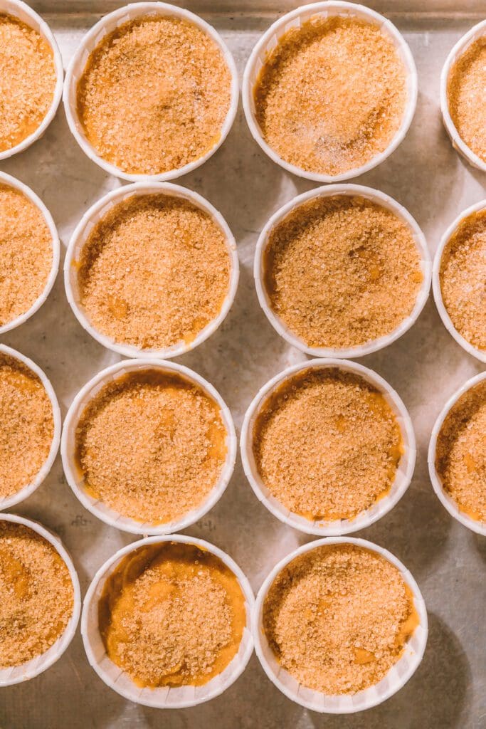 pumpkin muffin batter in cups topped with sugar