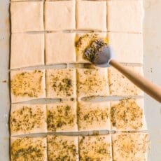 Brushing pull apart garlic bread with herb butter.