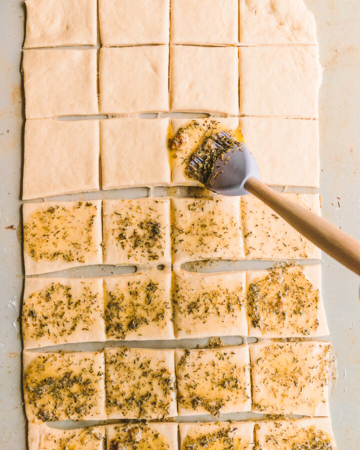 Brushing pull apart garlic bread with herb butter.